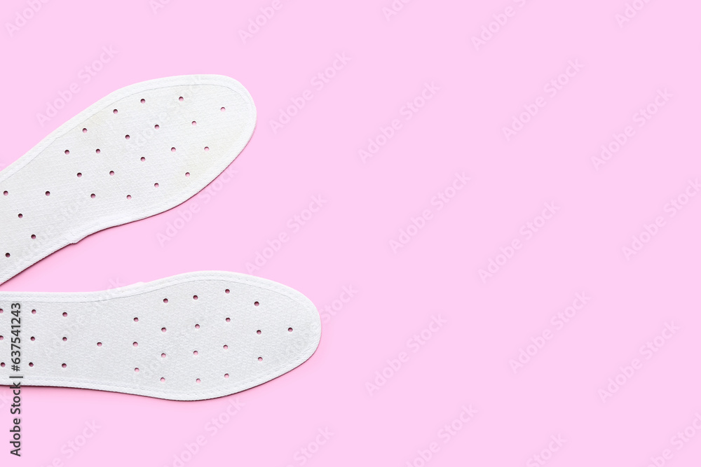 Pair of orthopedic insoles on pink background