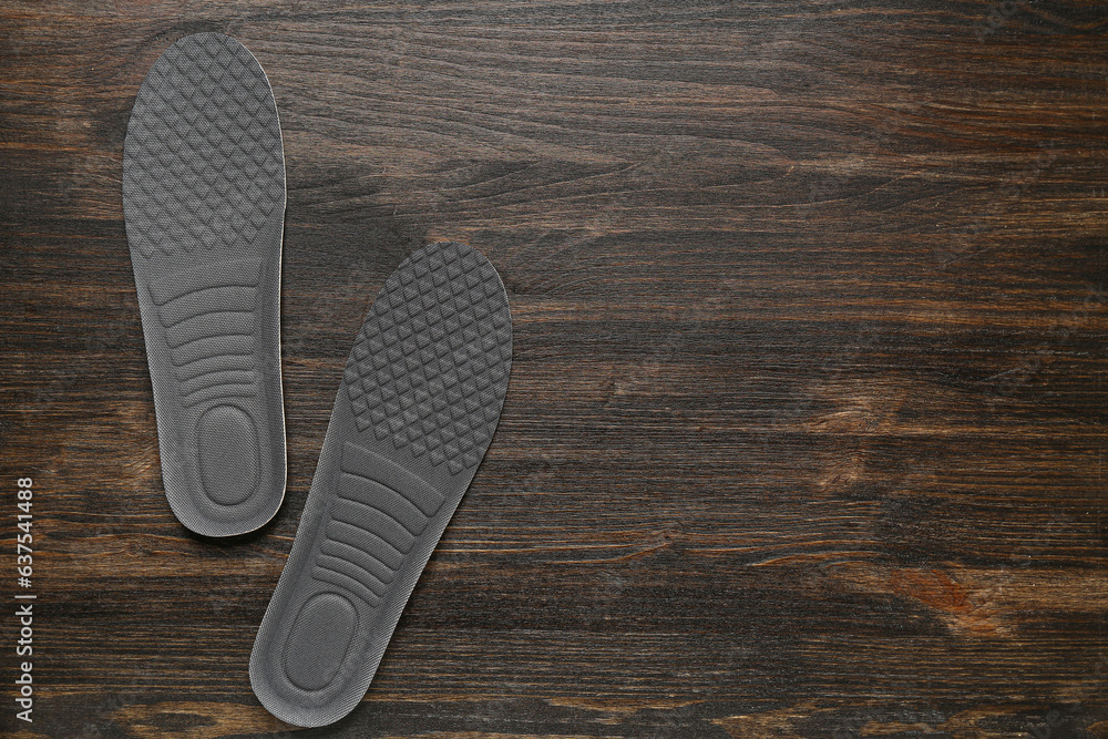 Pair of orthopedic insoles on dark wooden background