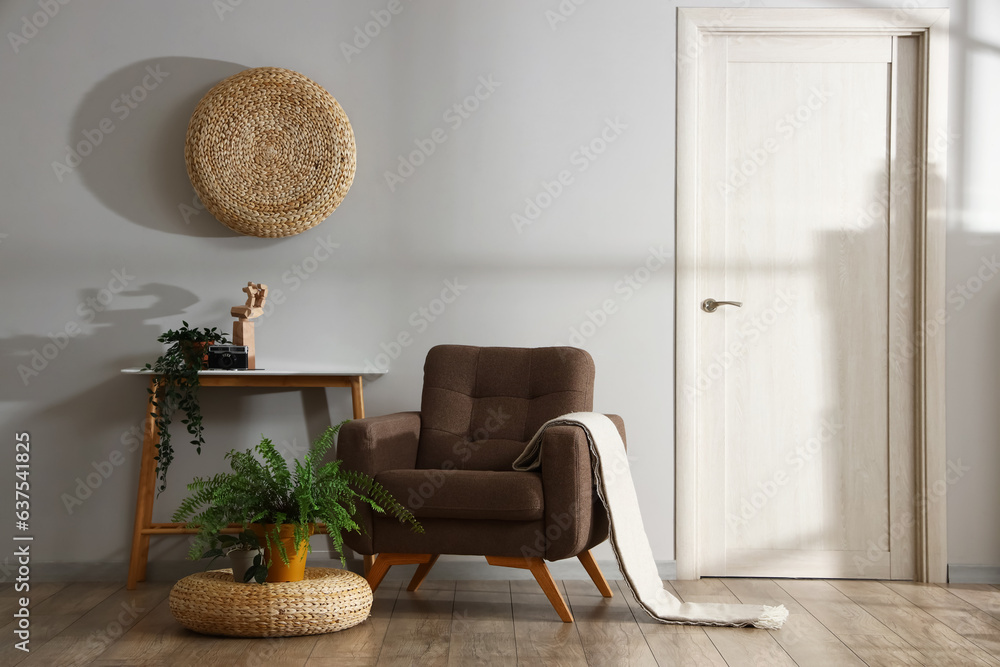 Interior of living room with soft armchair, rattan poufs and table