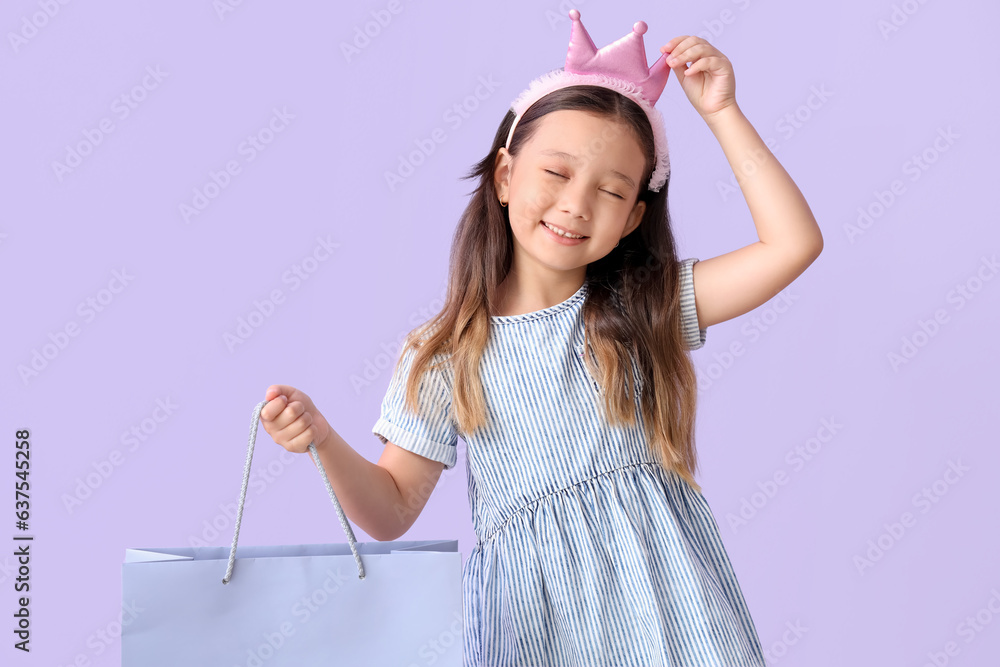 Cute little girl with shopping bag on lilac background