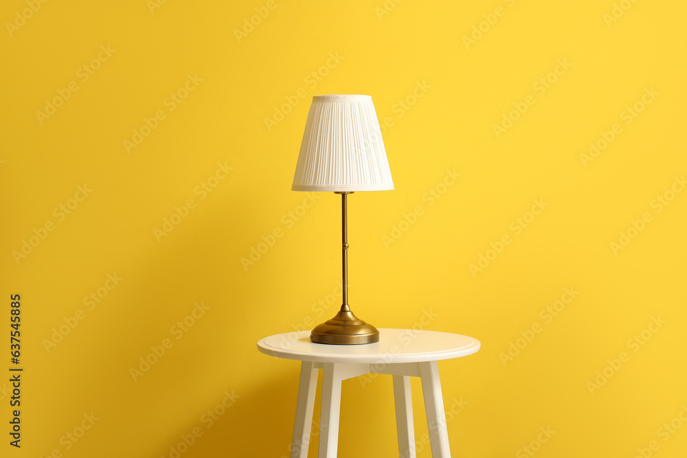 Small table with lamp near yellow wall