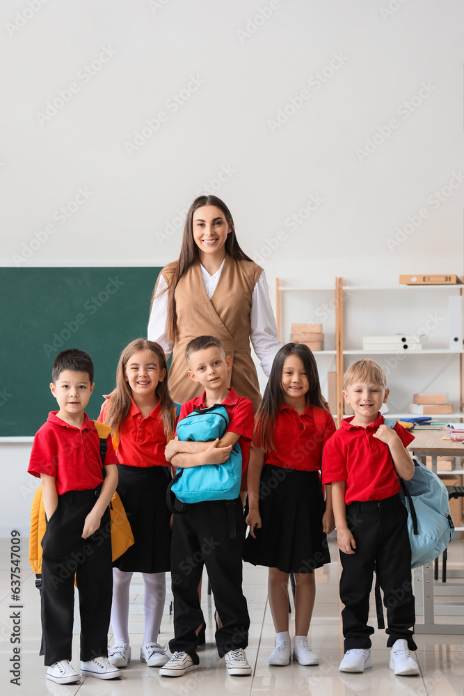 Female teacher with little school children in classroom