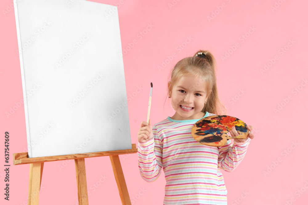 Cute little girl with paint palette, brush and easel on pink background