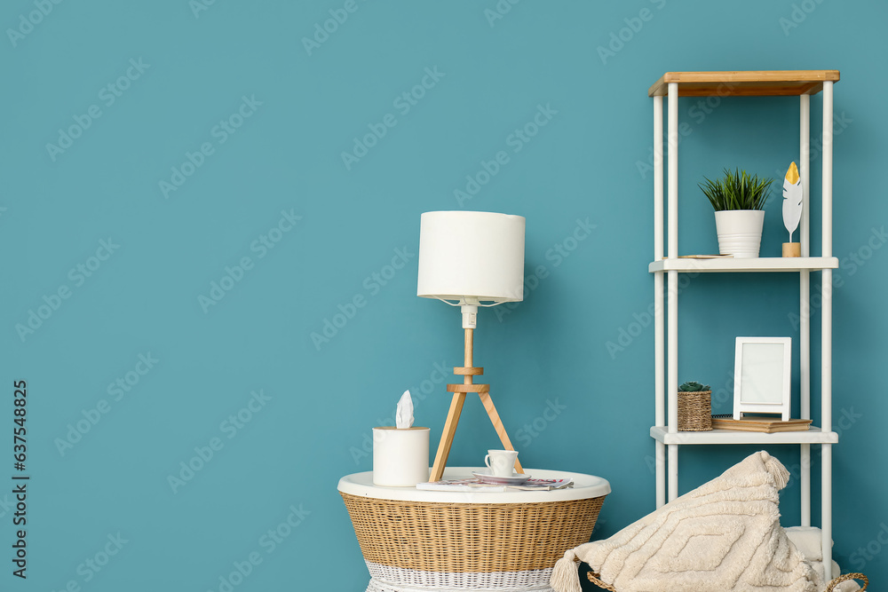 Lamp on small table and shelving unit near blue wall