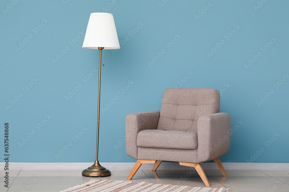 Cozy grey armchair and standard lamp near blue wall