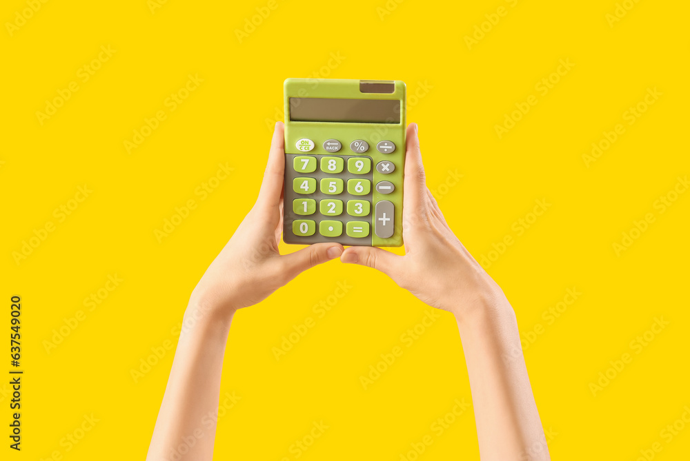 Hands with calculator on yellow background