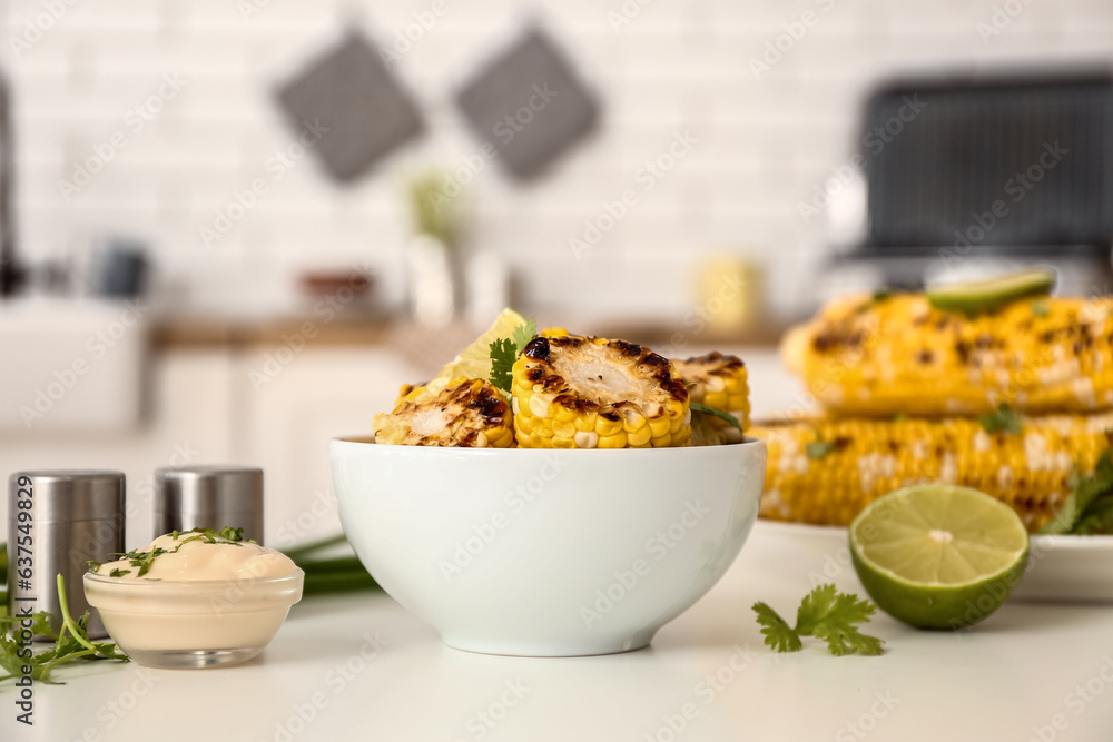 Bowl with tasty grilled corn on table in kitchen, closeup