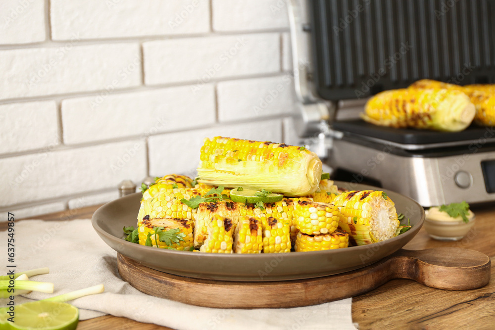 Plate with tasty grilled corn on wooden kitchen counter