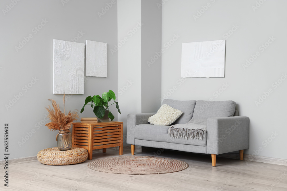 Interior of modern living room with paintings, grey sofa and houseplant