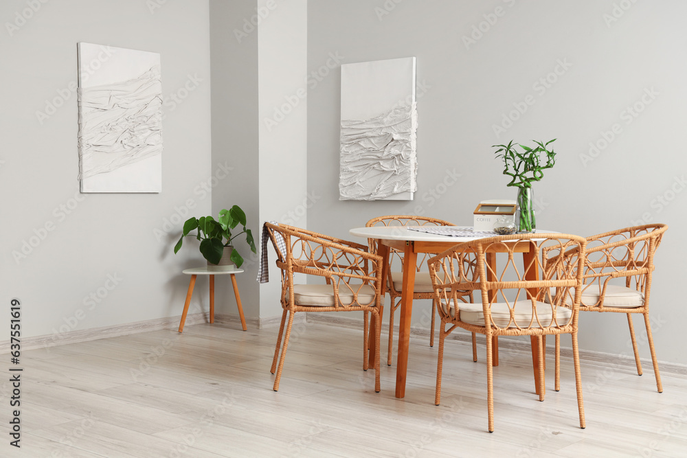 Interior of modern dining room with paintings, table and houseplant