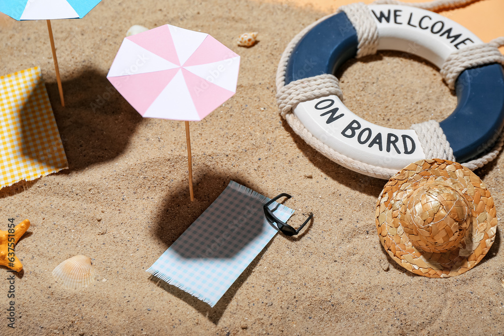 Creative summer composition with mini umbrellas, beach accessories and sand on beige background