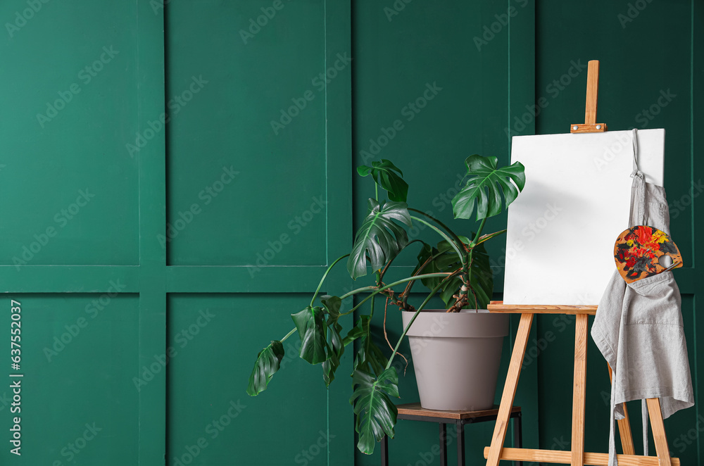 Wooden easel with blank canvas near green wall