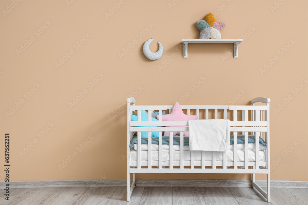 Interior of childrens room with crib near beige wall