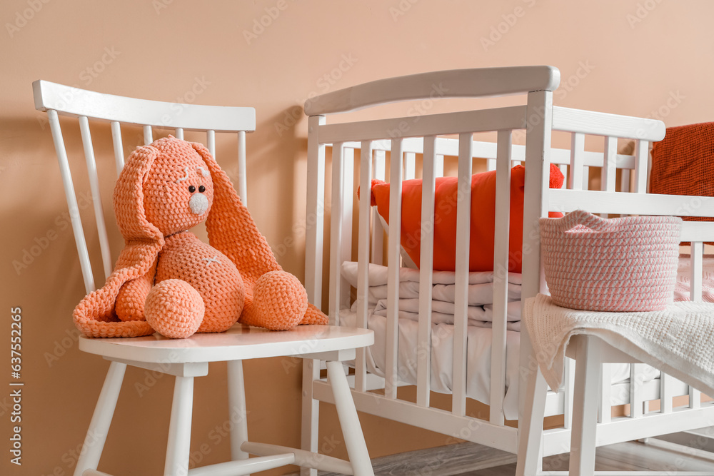 Interior of childrens room with crib and toys near beige wall