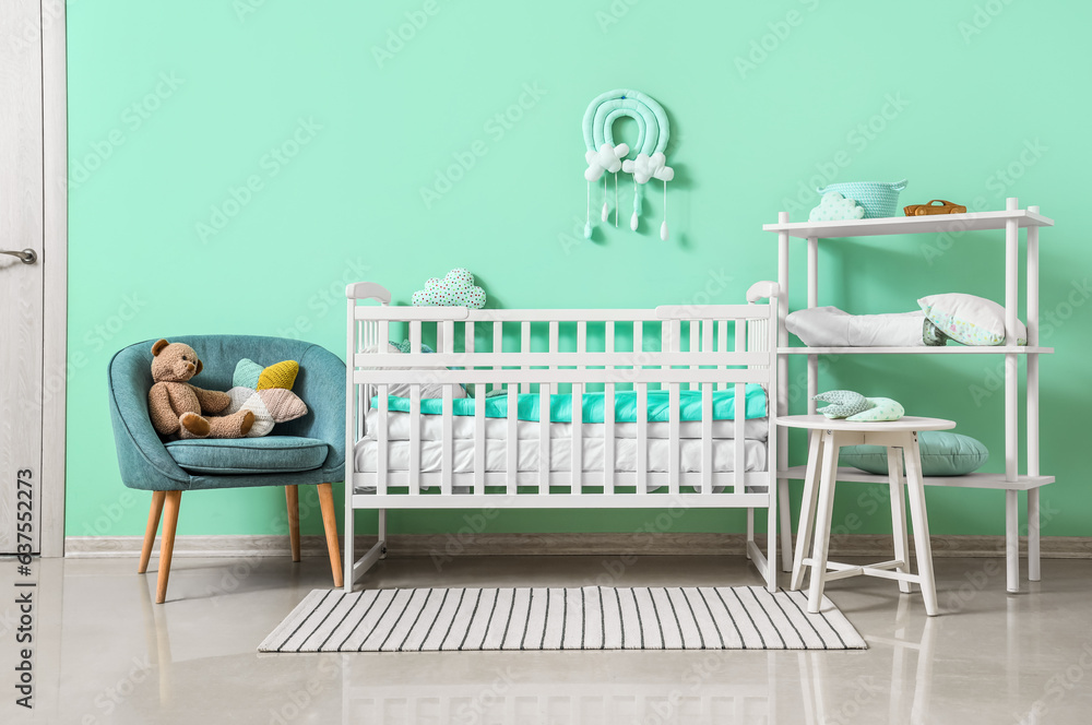 Interior of childrens room with crib and armchair near turquoise wall