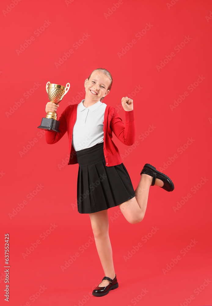 Cute little schoolgirl with gold cup on red background