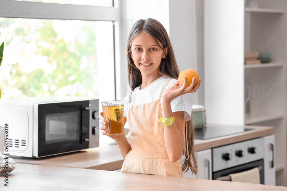 Little girl with glass of juice and peach in kitchen