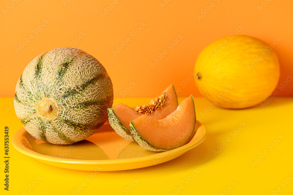 Plate with tasty ripe melons on orange background