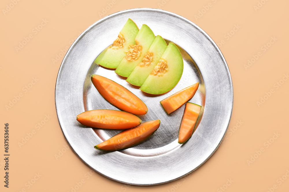 Plate with slices of tasty ripe melon on orange background