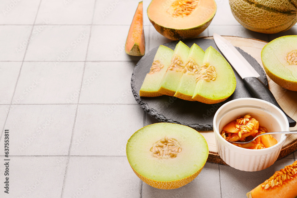 Boards with tasty ripe melons on white tile background