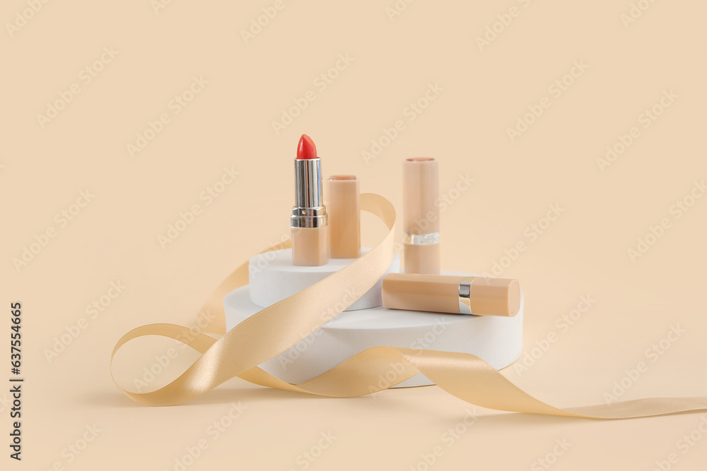 Lipsticks with podiums and ribbon on light background