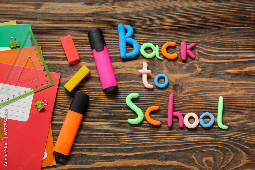 Text BACK TO SCHOOL and stationery on wooden background