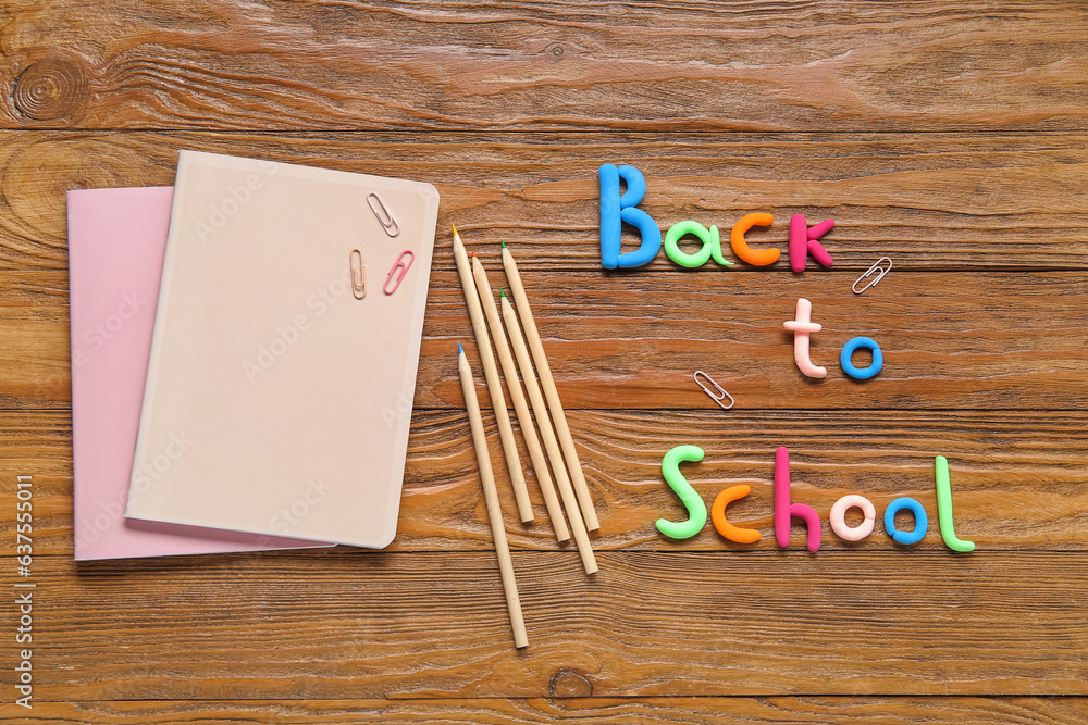 Text BACK TO SCHOOL and stationery on wooden background