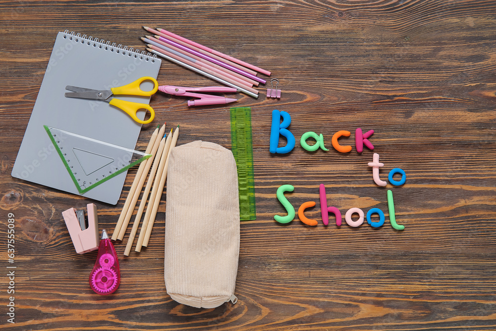 Text BACK TO SCHOOL and stationery on wooden background