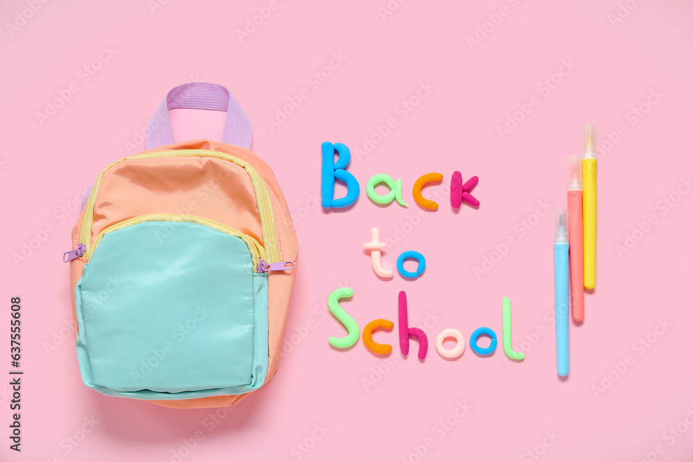 Text BACK TO SCHOOL, backpack and markers on pink background