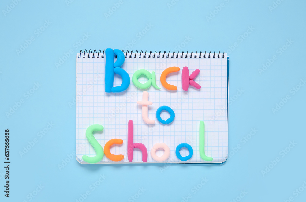 Text BACK TO SCHOOL with notebook on light blue background