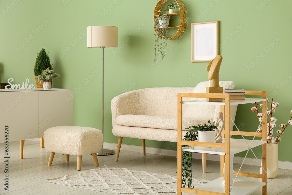 Interior of stylish living room with white sofa, pouf and shelving unit