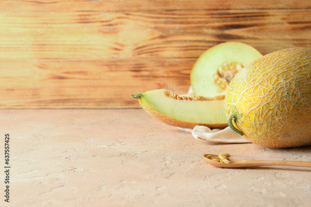 Sweet melons and spoon with seeds on pink table