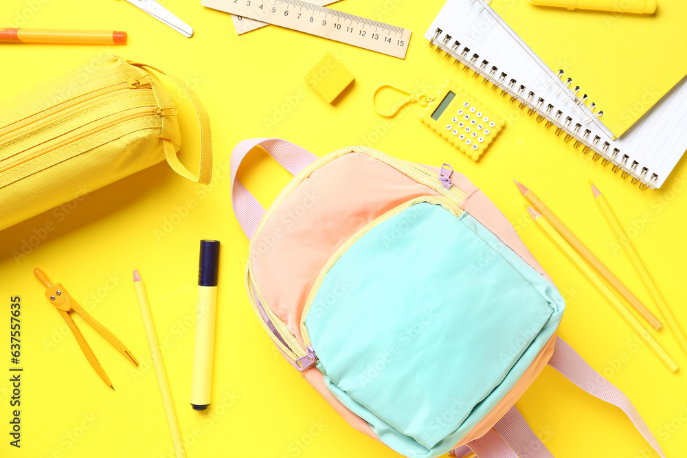 Stylish school backpack and pencil case with different stationery supplies on yellow background