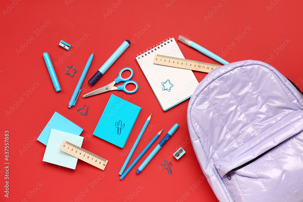 Stylish school backpack with different stationery supplies on red background