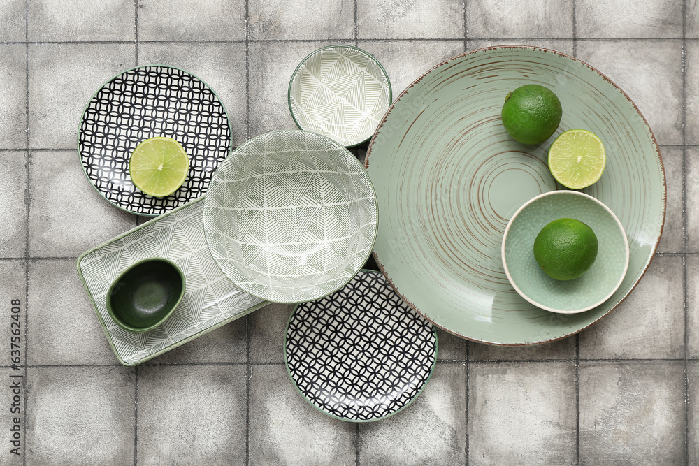 Beautiful table setting with green ceramic plates and limes on grey tiled background