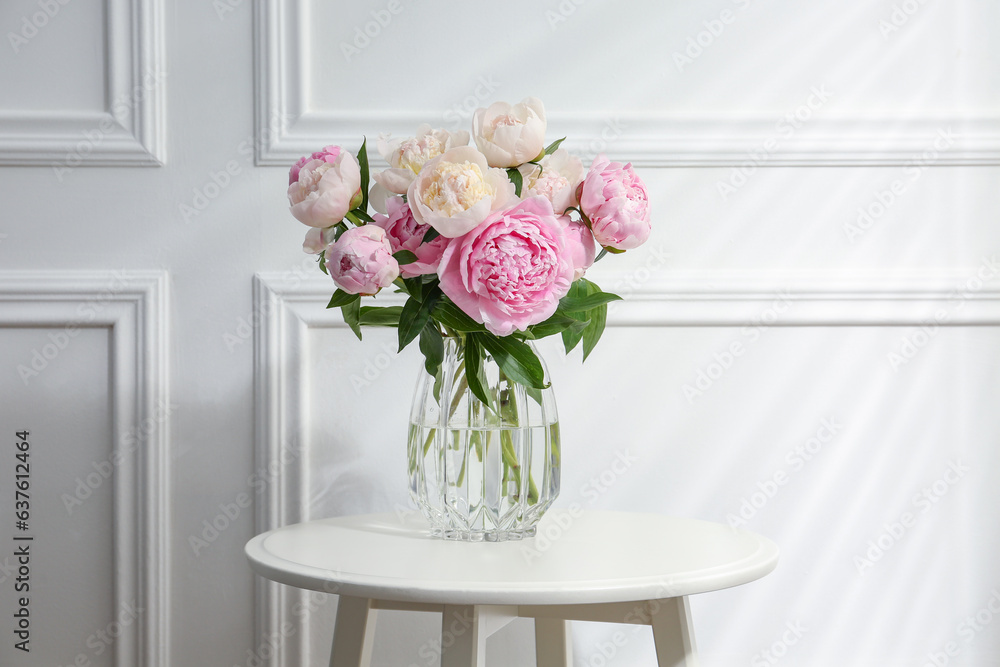 Beautiful peonies in glass vase on white table