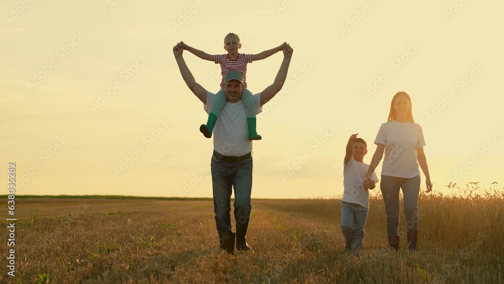 Daughter on shoulders of dad, mom, son, walk hand in hand outdoor. Happy farmers family with childre