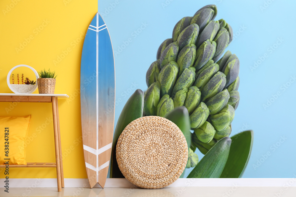 Wooden surfboard with table and decor near wall with printed hyacinth plant