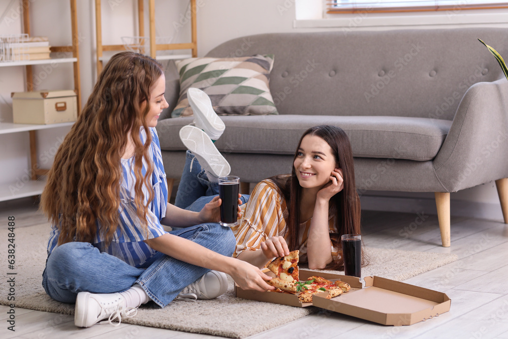 Young women with tasty pizza and cola at home