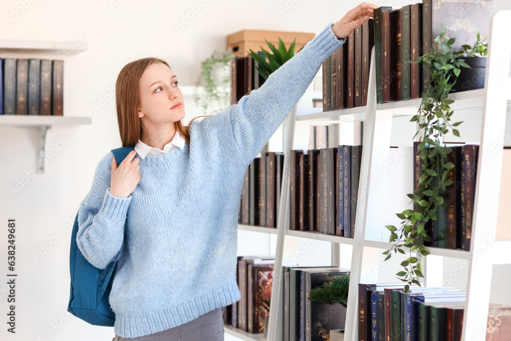 Female student taking book from shelf in library