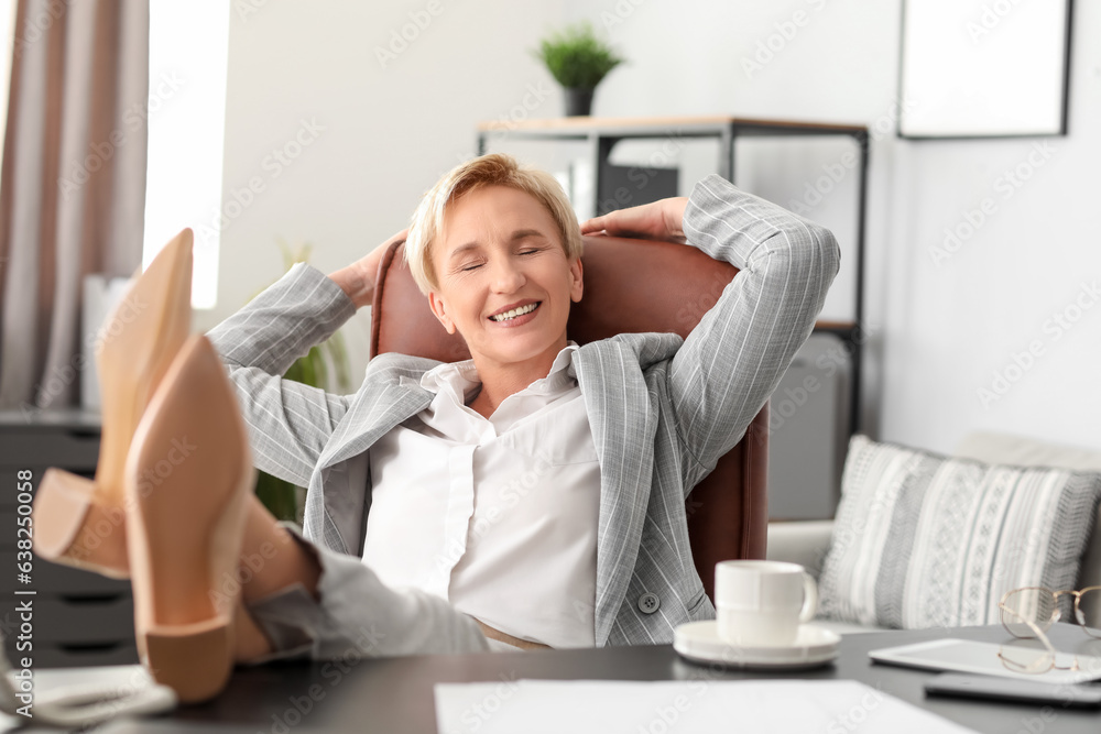 Happy mature businesswoman relaxing in office