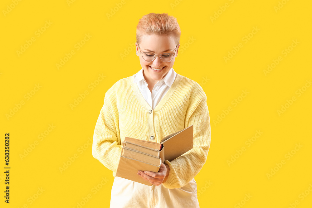 Female student with books on yellow background