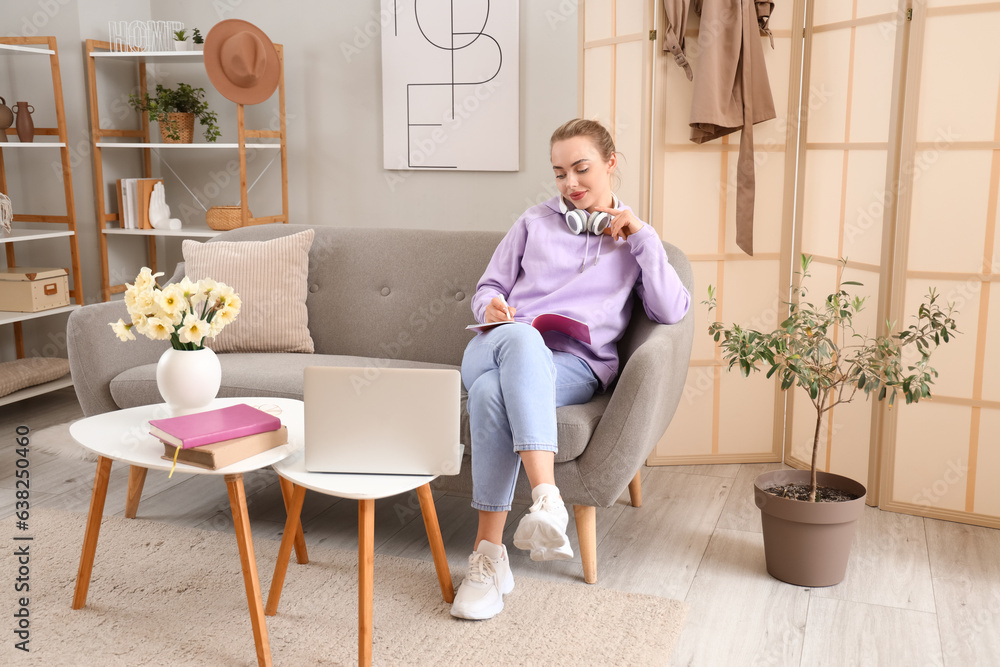 Female student in headphones doing homework at home