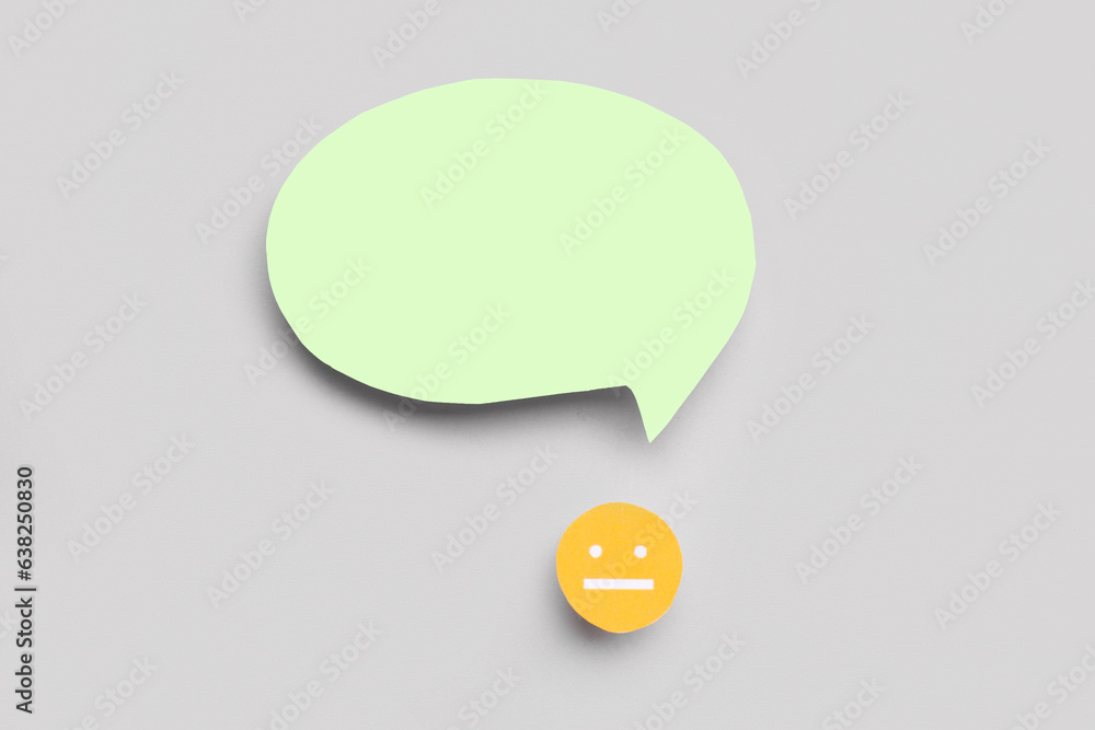 Paper face with blank speech bubble on grey background