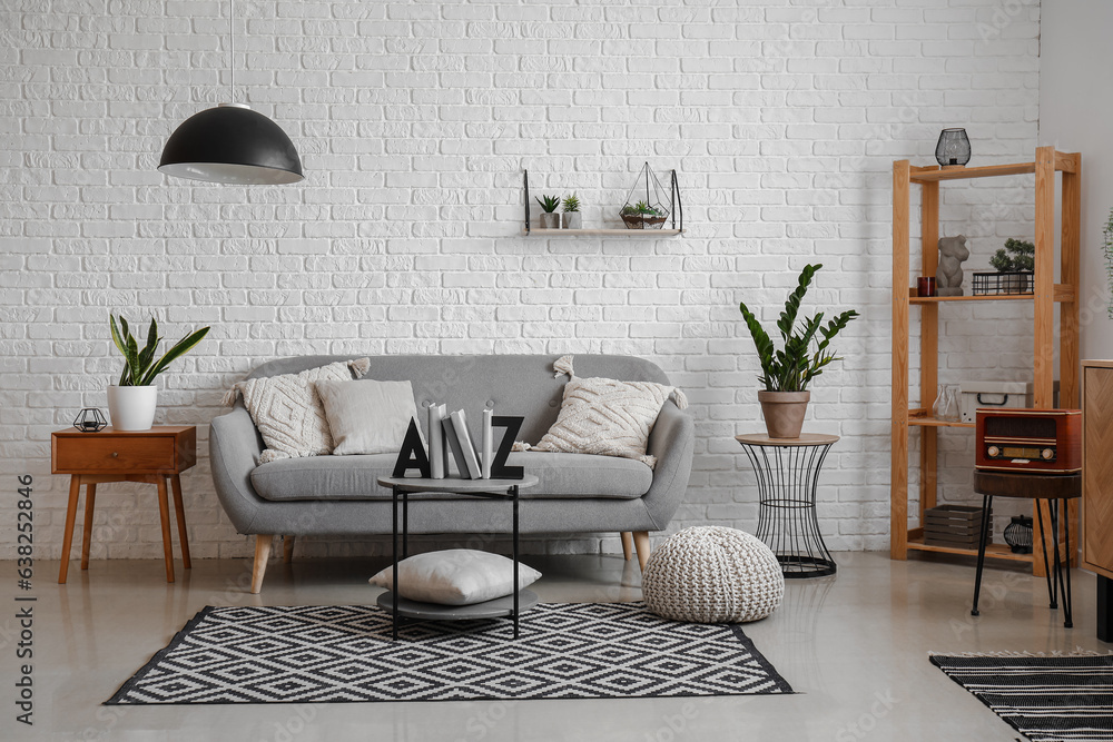 Interior of living room with sofa, houseplants and stylish holder for books on coffee table