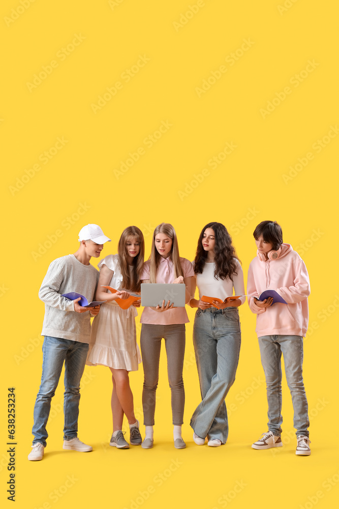 Group of students with laptop and copybooks on yellow background