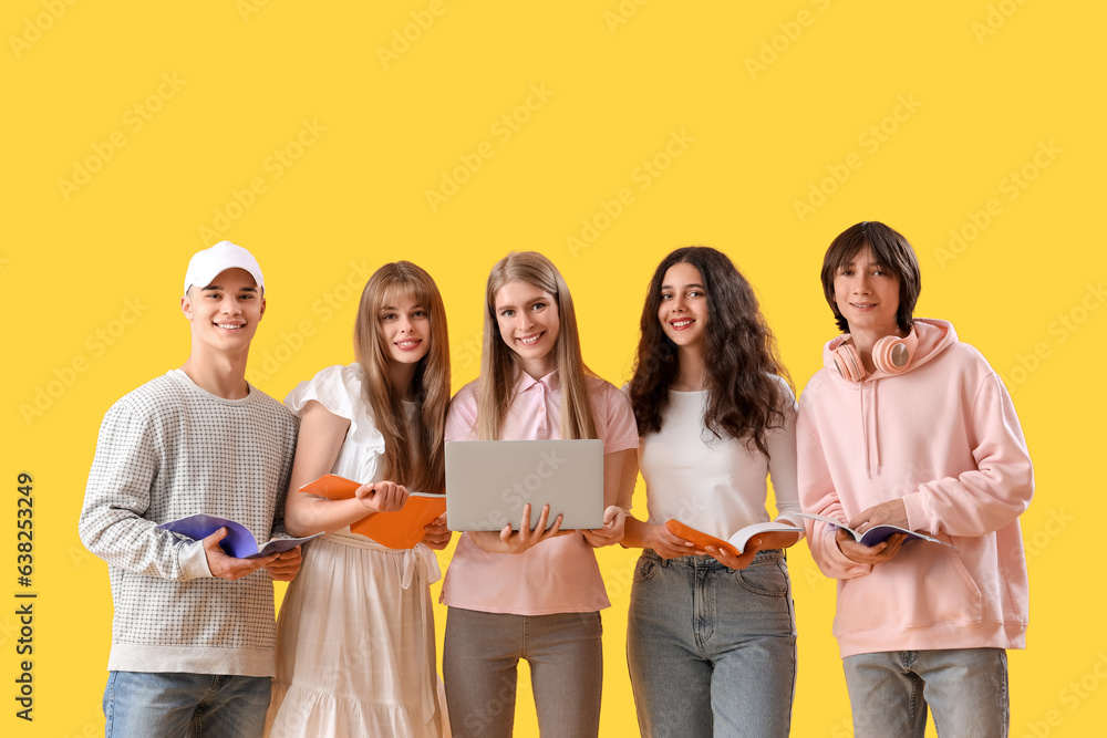 Group of students with laptop and copybooks on yellow background