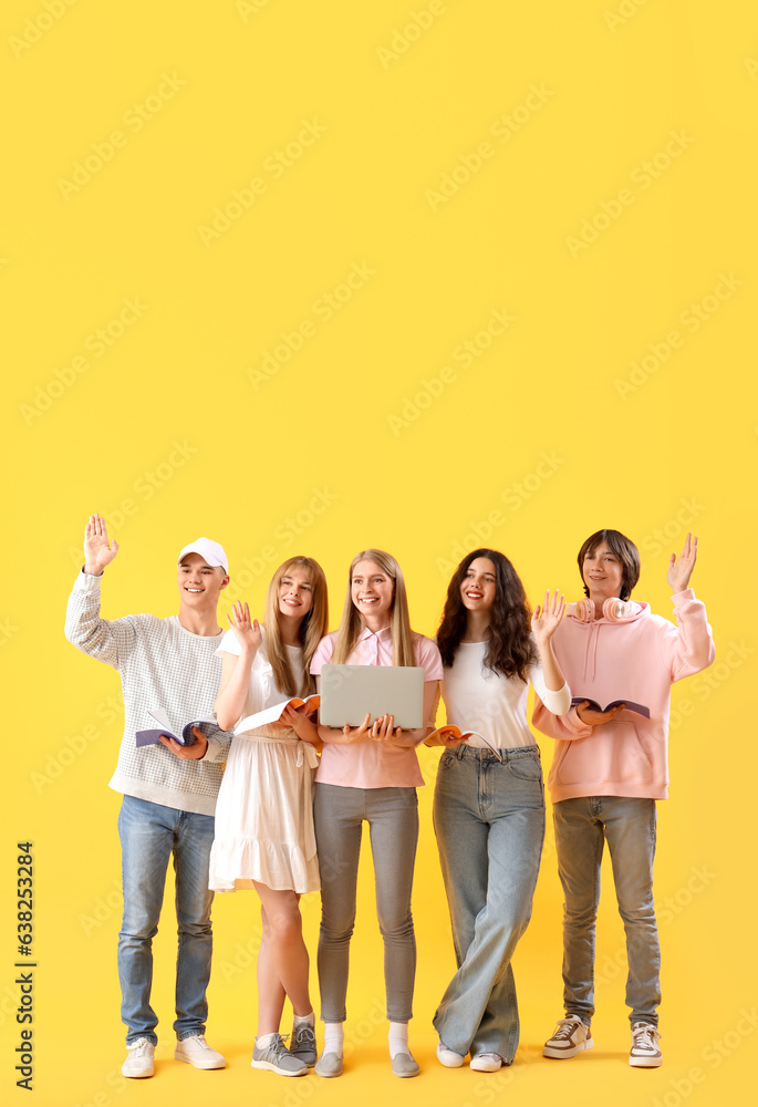 Group of students with laptop and copybooks on yellow background