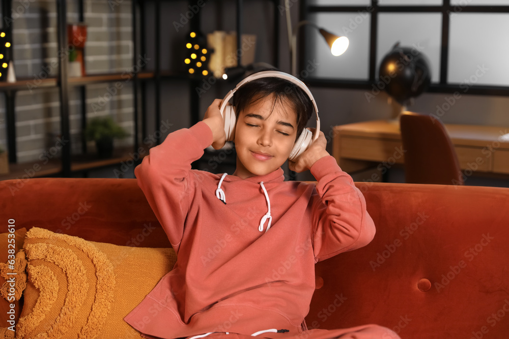 Little boy with headphones listening to music at home late in evening