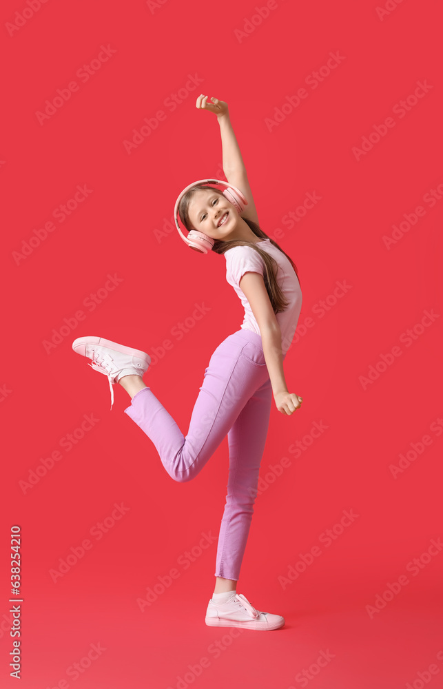 Little girl in headphones dancing on red background